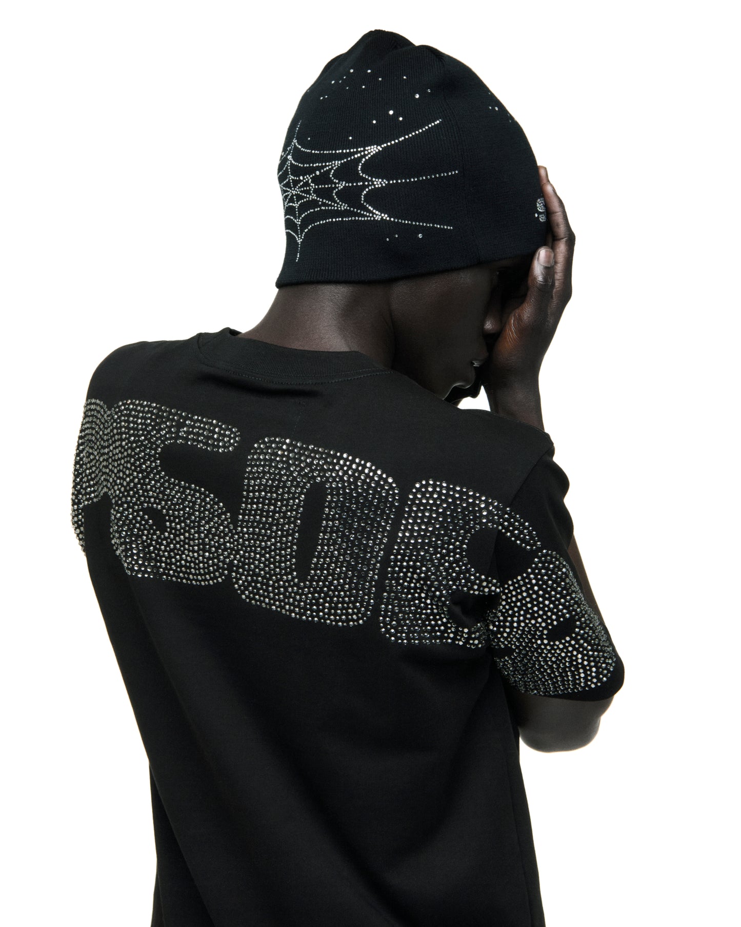 Black cotton tee with large rhinestone graphic on back, paired with a rhinestone spiderweb beanie.