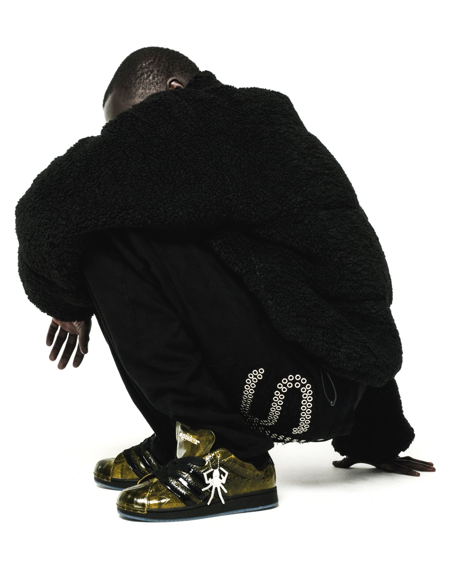 SP5DER x ADIDAS SUPERSTAR in glossy cracked patent leather, gold with black stripes, spider charm, and translucent outsole.