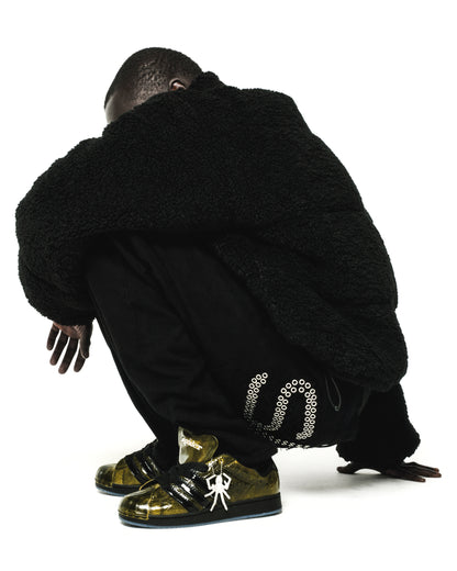 SP5DER x ADIDAS SUPERSTAR in glossy cracked patent leather, gold with black stripes, spider charm, and translucent outsole.