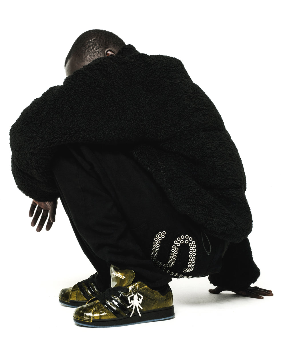 SP5DER x ADIDAS SUPERSTAR in glossy cracked patent leather, gold with black stripes, spider charm, and translucent outsole.