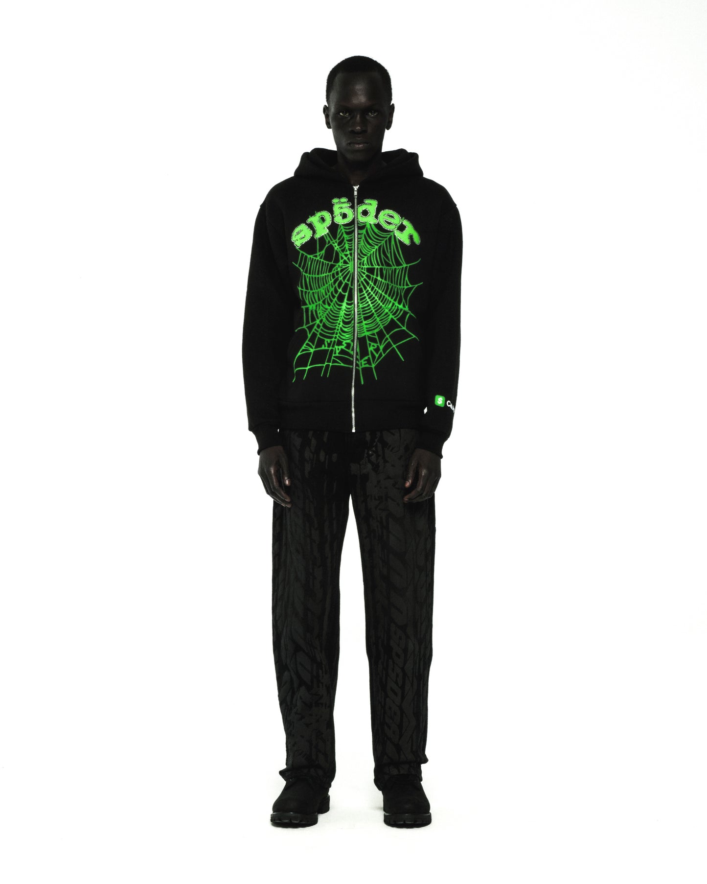 Black cotton fleece zip hoodie with green rhinestone phantom web and "Sp5der" logo.