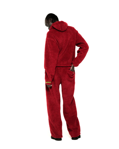 Red sherpa fleece hooded zip-up jacket and matching pants with a yellow rubberized logo patch on the wrist.