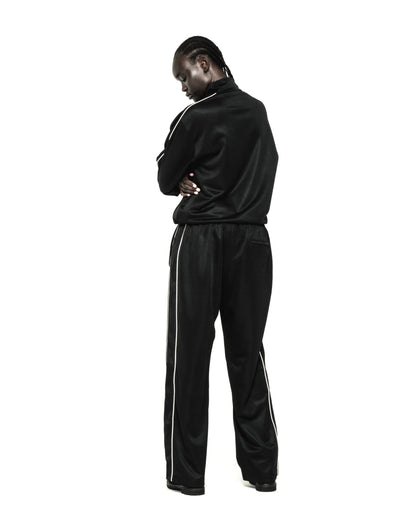 Black polyester track jacket and pants with white piping, worn by a person facing away.