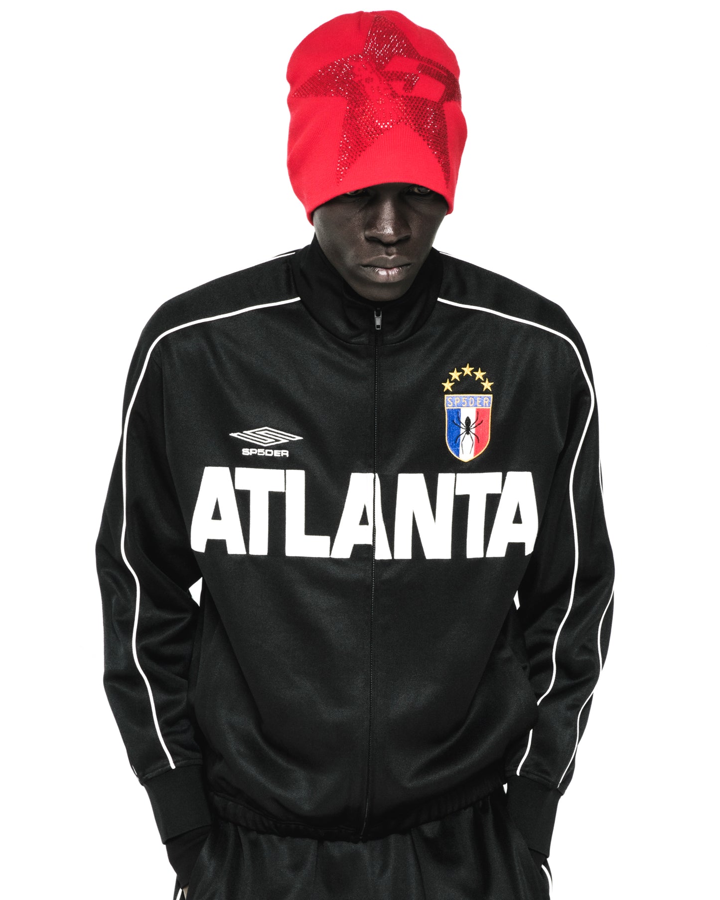 Black polyester ATLANTA TRACK JACKET with white lettering, SP5DER crest, and red beanie.