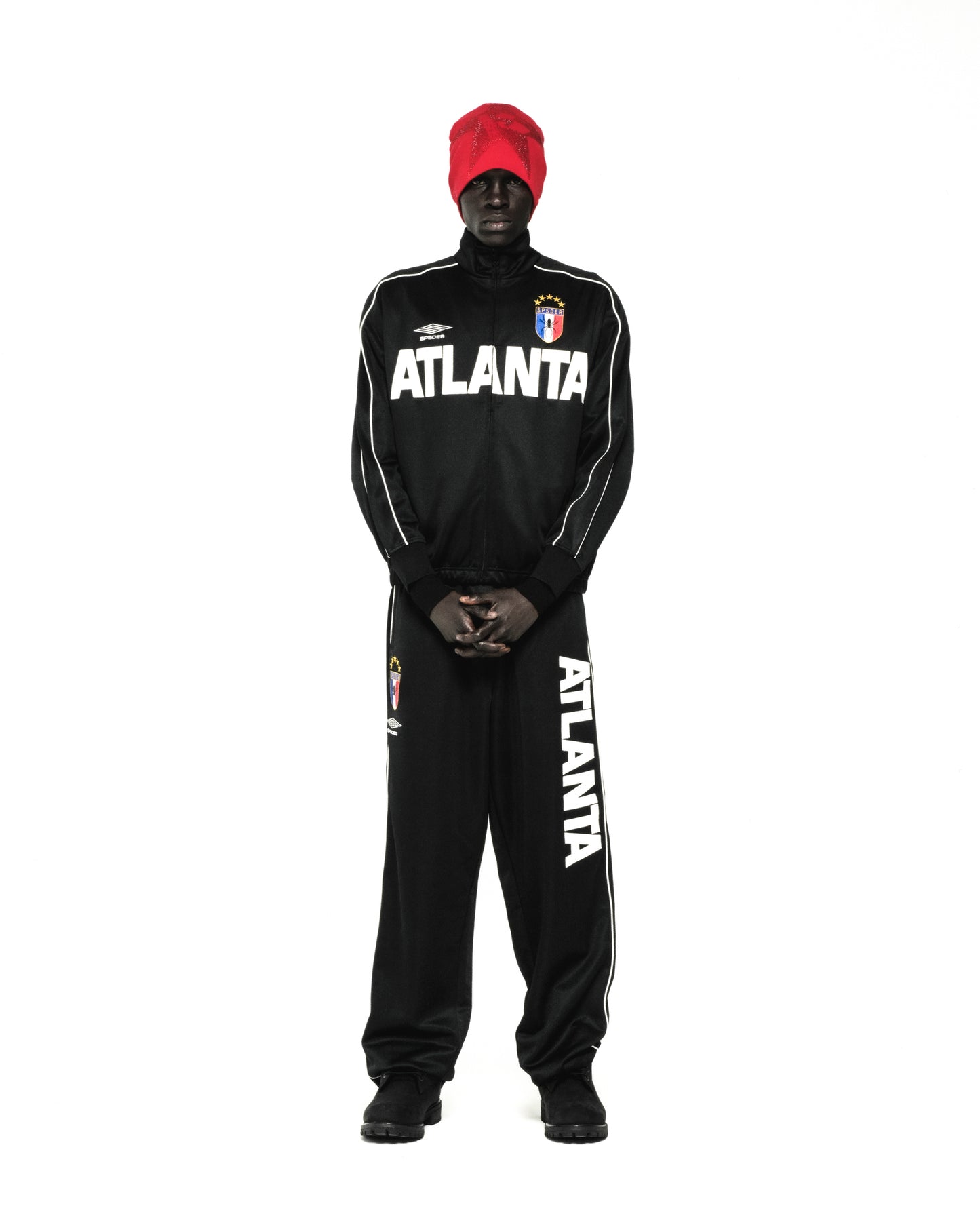 Black ATLANTA TRACK JACKET with white lettering, SP5DER crests, and contrasting piping, worn by a person.