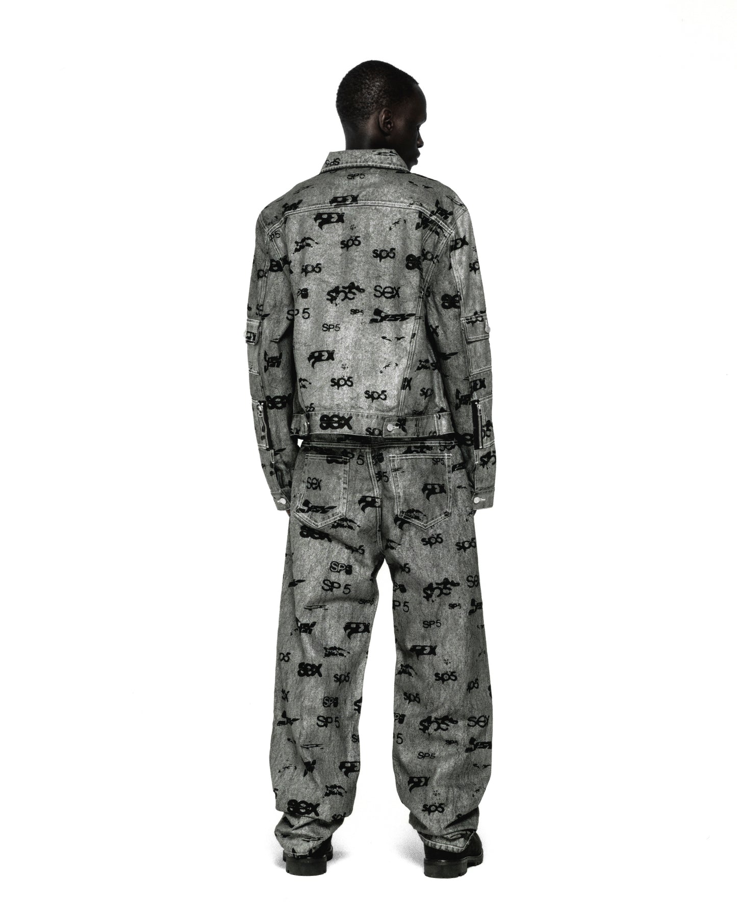 Model from behind wearing a grey denim trucker jacket and matching jeans with an all-over "SEX" print.