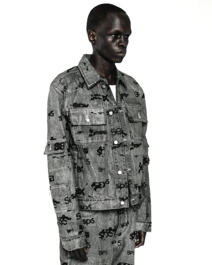 Black model wearing a gray denim trucker jacket with black all-over print, silver buttons, and arm pockets.