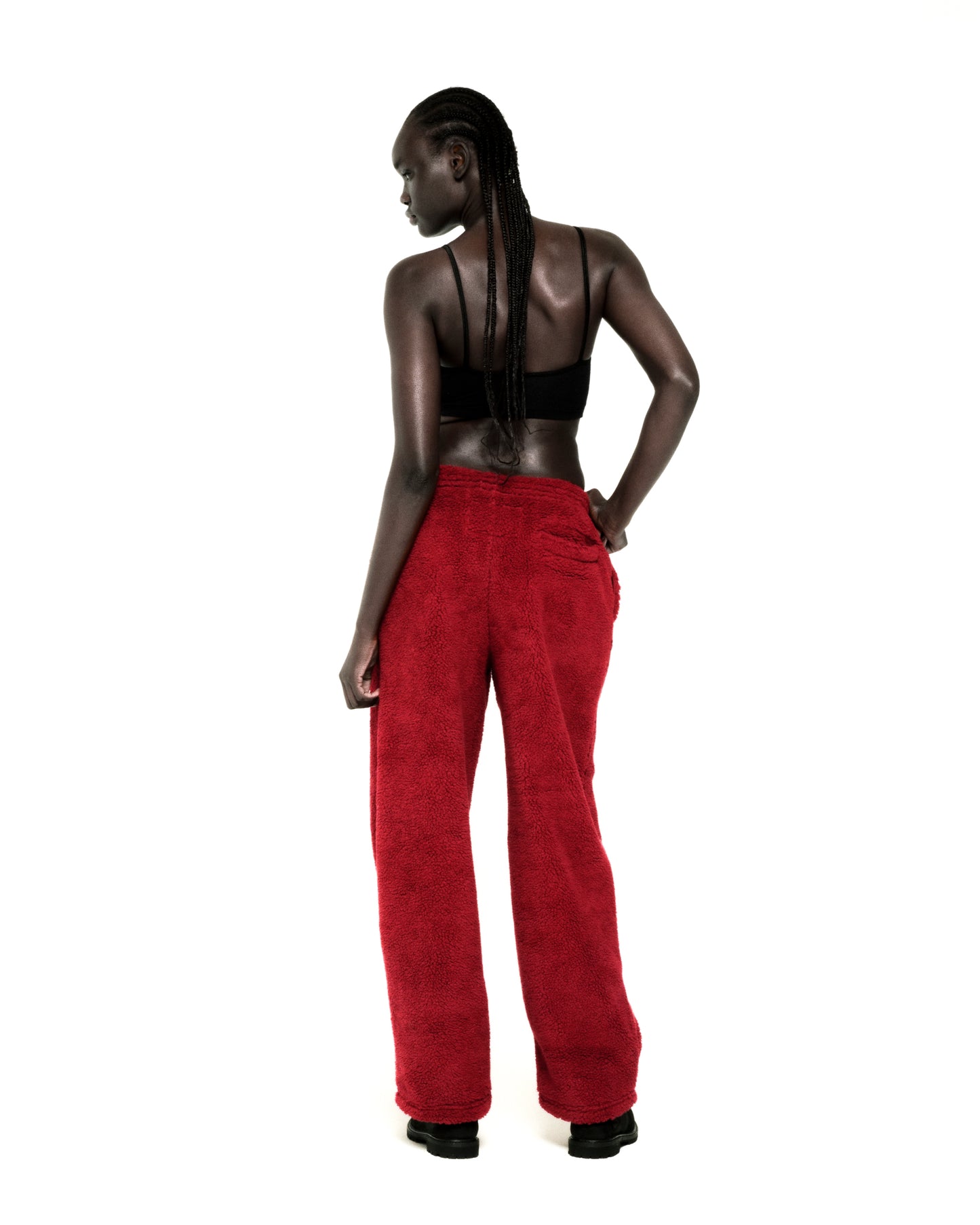 Model wearing red teddy fleece pants with a rubberized logo patch and a black bralette.