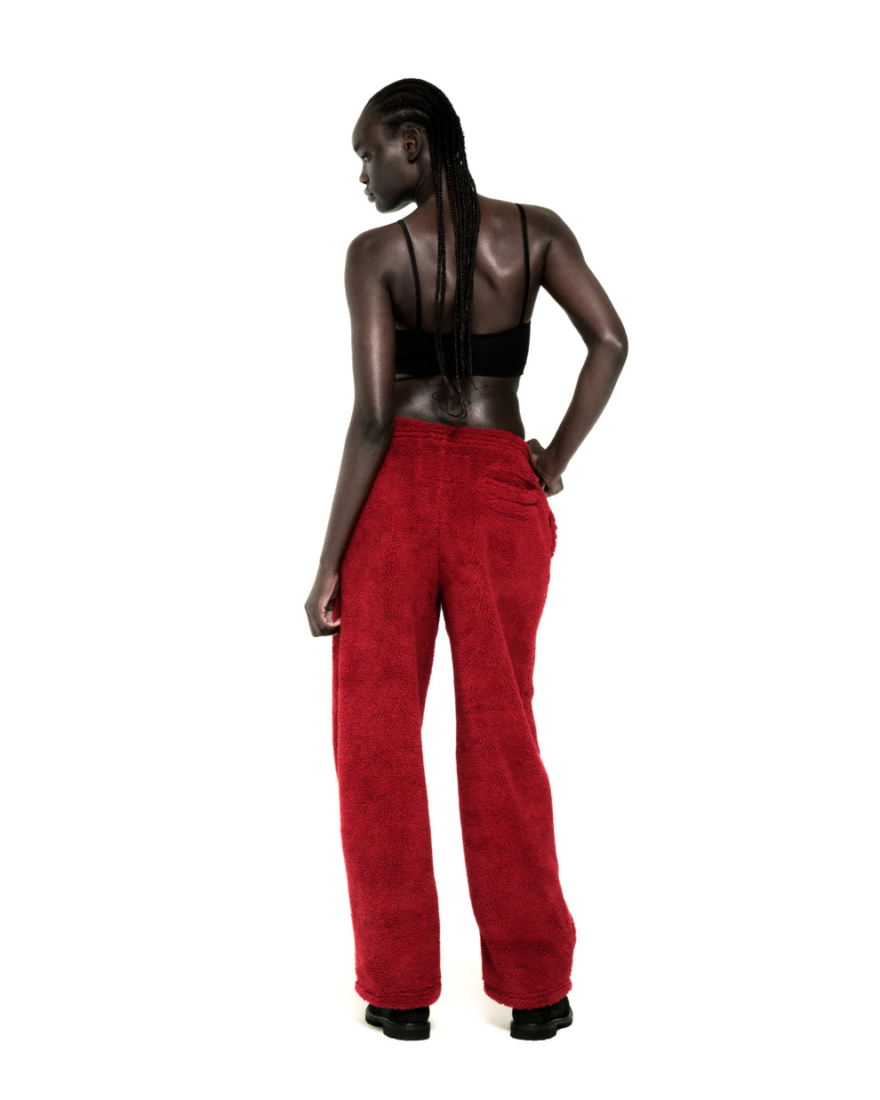 Model wearing red teddy fleece pants with a rubberized logo patch and a black bralette.
