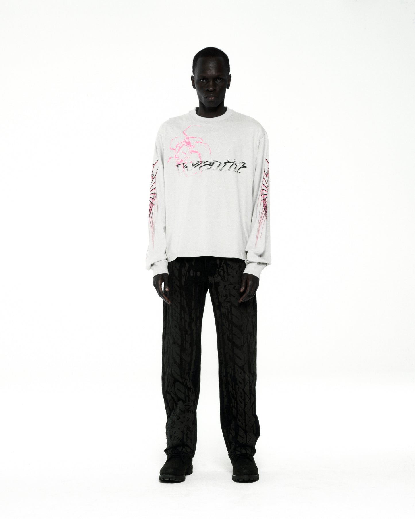 White 100% cotton WAIT LONGSLEEVE tee with pink and black graphic print on front and sleeves.