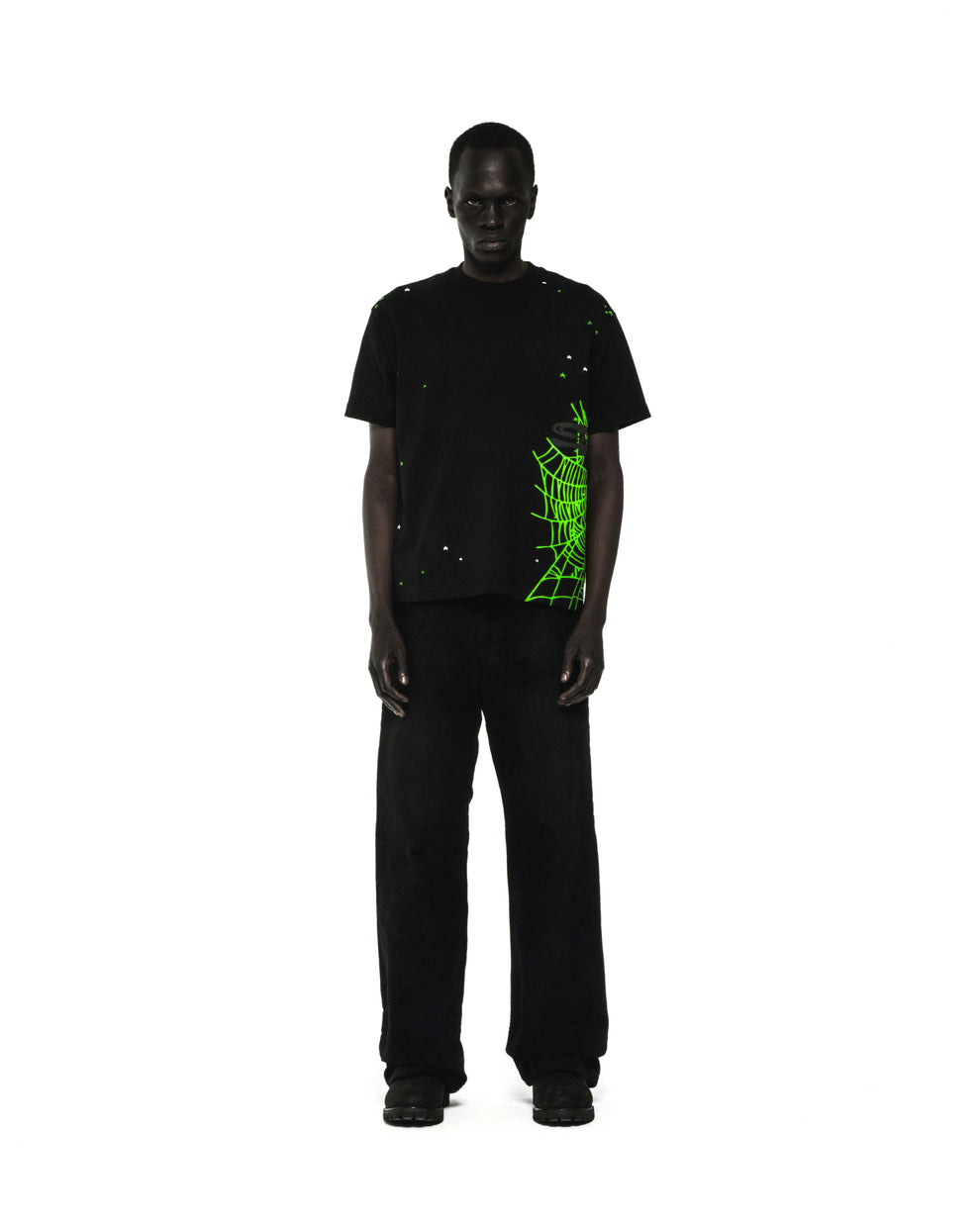 Black 100% cotton HEAVY WEB TEE with neon green spider web and star print, worn by a male model.