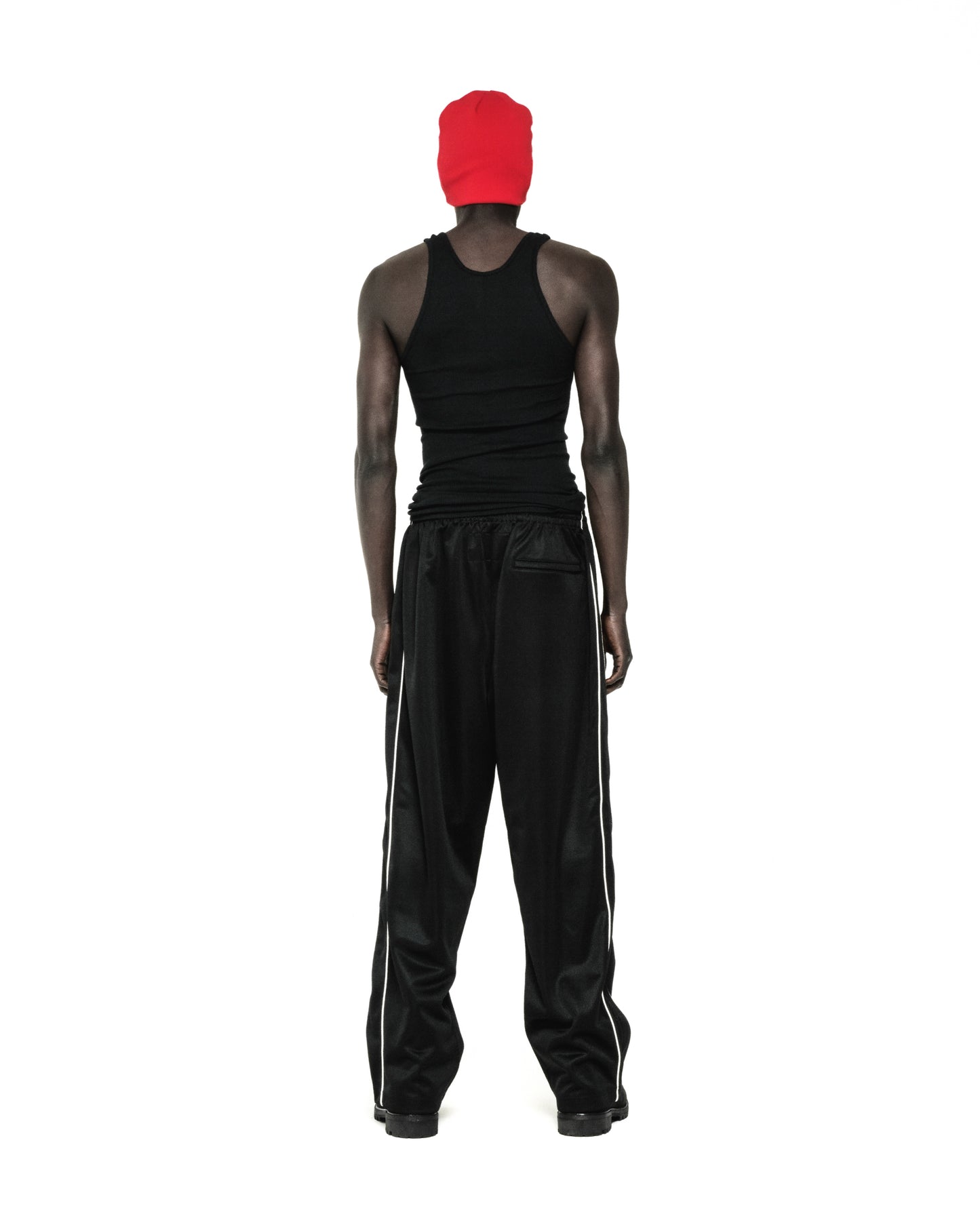 Black ATLANTA TRACK PANT with white side piping, worn by a person facing away.