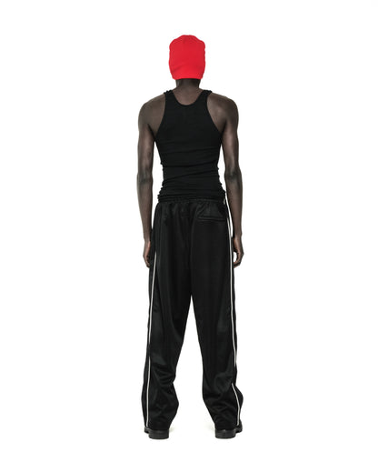 Black ATLANTA TRACK PANT with white side piping, worn by a person facing away.