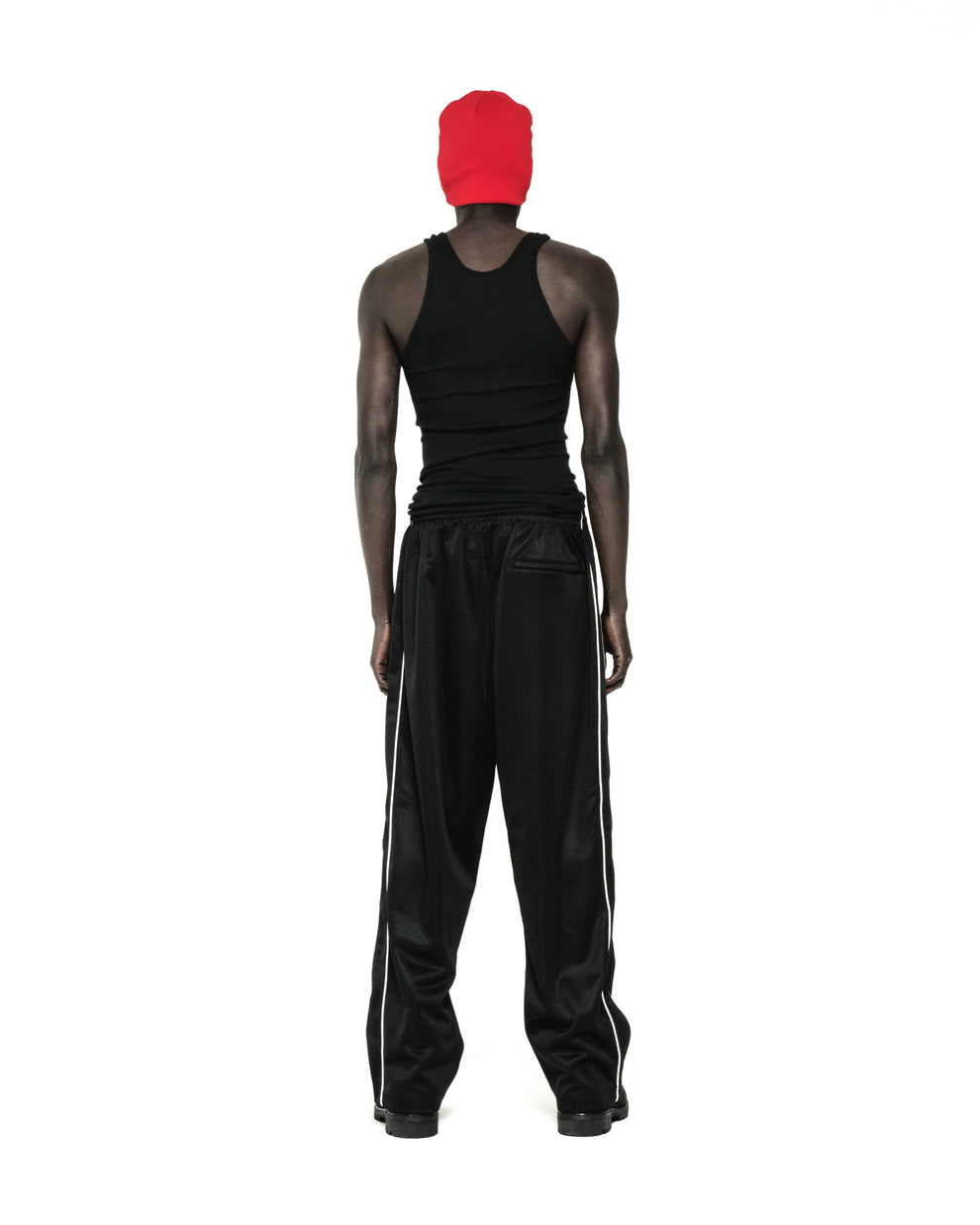 Black ATLANTA TRACK PANT with white side piping, worn by a person facing away.