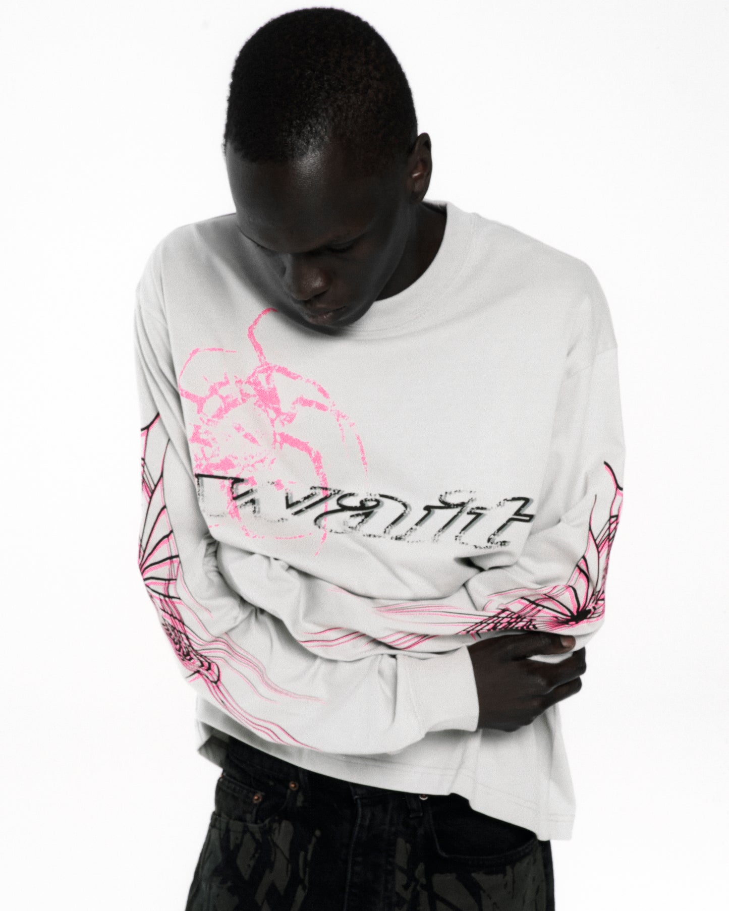 White 100% cotton long sleeve tee with pink and black graphic print on front and sleeves.