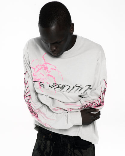 White 100% cotton long sleeve tee with pink and black graphic print on front and sleeves.