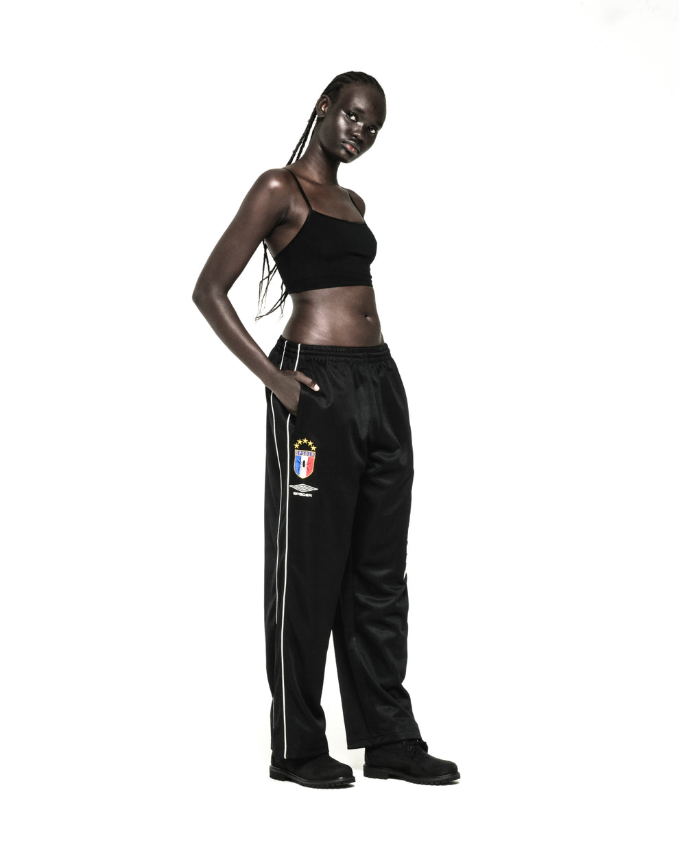 Black ATLANTA TRACK PANT with SP5DER crest, white side piping, and wide-leg silhouette.