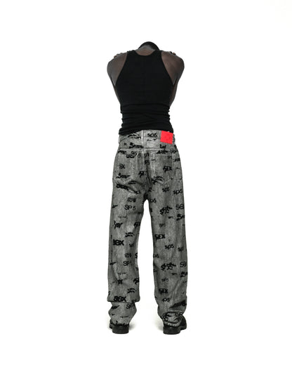 Gray denim pants with all-over black "SEX" and "SP5DER" print, red leather patch, and straight leg fit.