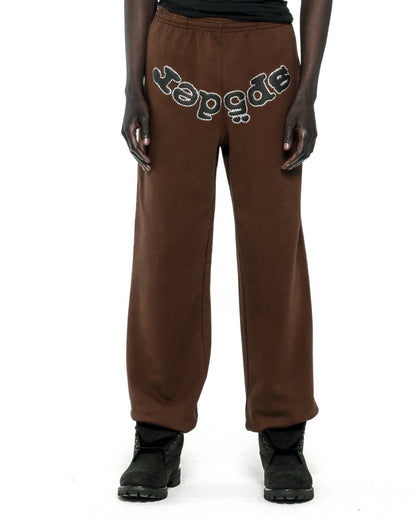 Brown cotton fleece sweatpants with "SP5DER" text in rhinestones across the crotch.