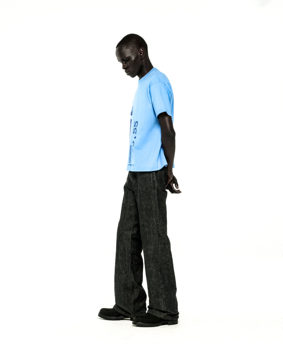 Man in light blue cotton COMMERCE TEE with graphic print and dark pants.