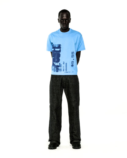 Light blue cotton COMMERCE TEE with dark blue graphic print, paired with dark jeans.