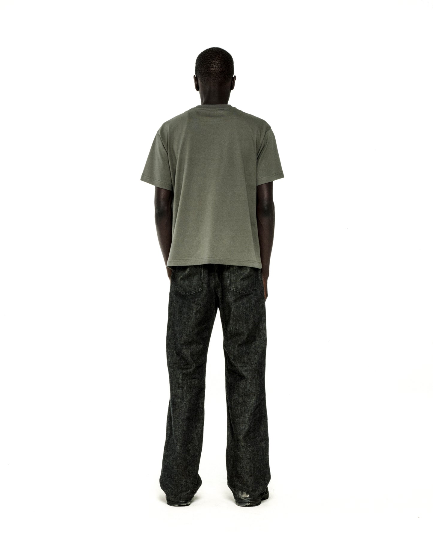 Man in standard fit, olive green cotton COMMERCE TEE and dark wash jeans, back view.