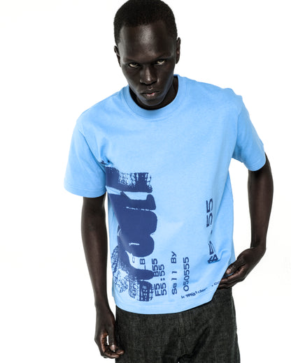 Man in light blue cotton Commerce Tee with dark blue graphic print and dark jeans.