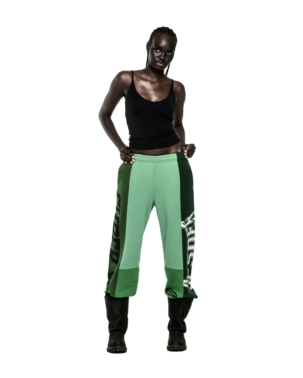 SUPERFIVE SWEATPANT: Model in wide-leg, contrast-paneled green cotton fleece sweatpants with graphic print and raw hem.