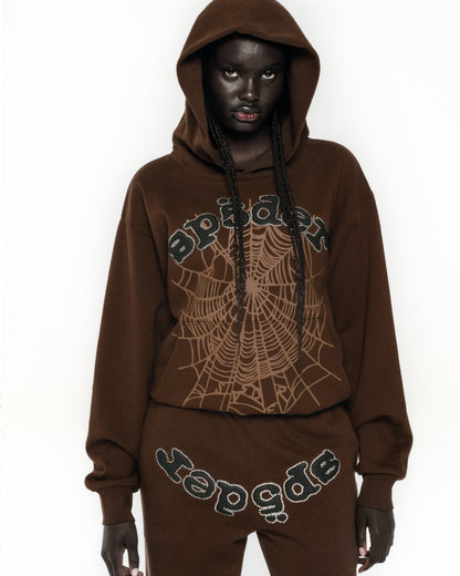 Model wearing a brown fleece hoodie with rhinestone spider web and text, matching sweatpants.