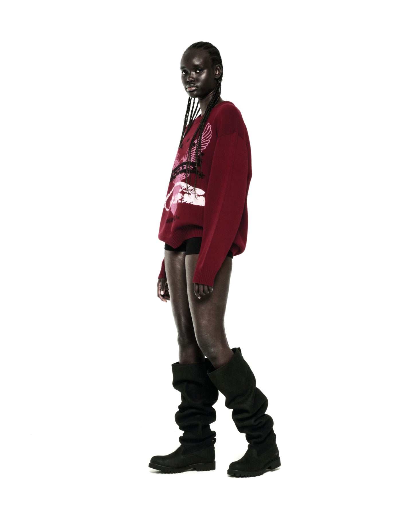 Dark-skinned model wearing a red knit sweater with a graphic print, ribbed collar, hem, and cuffs.