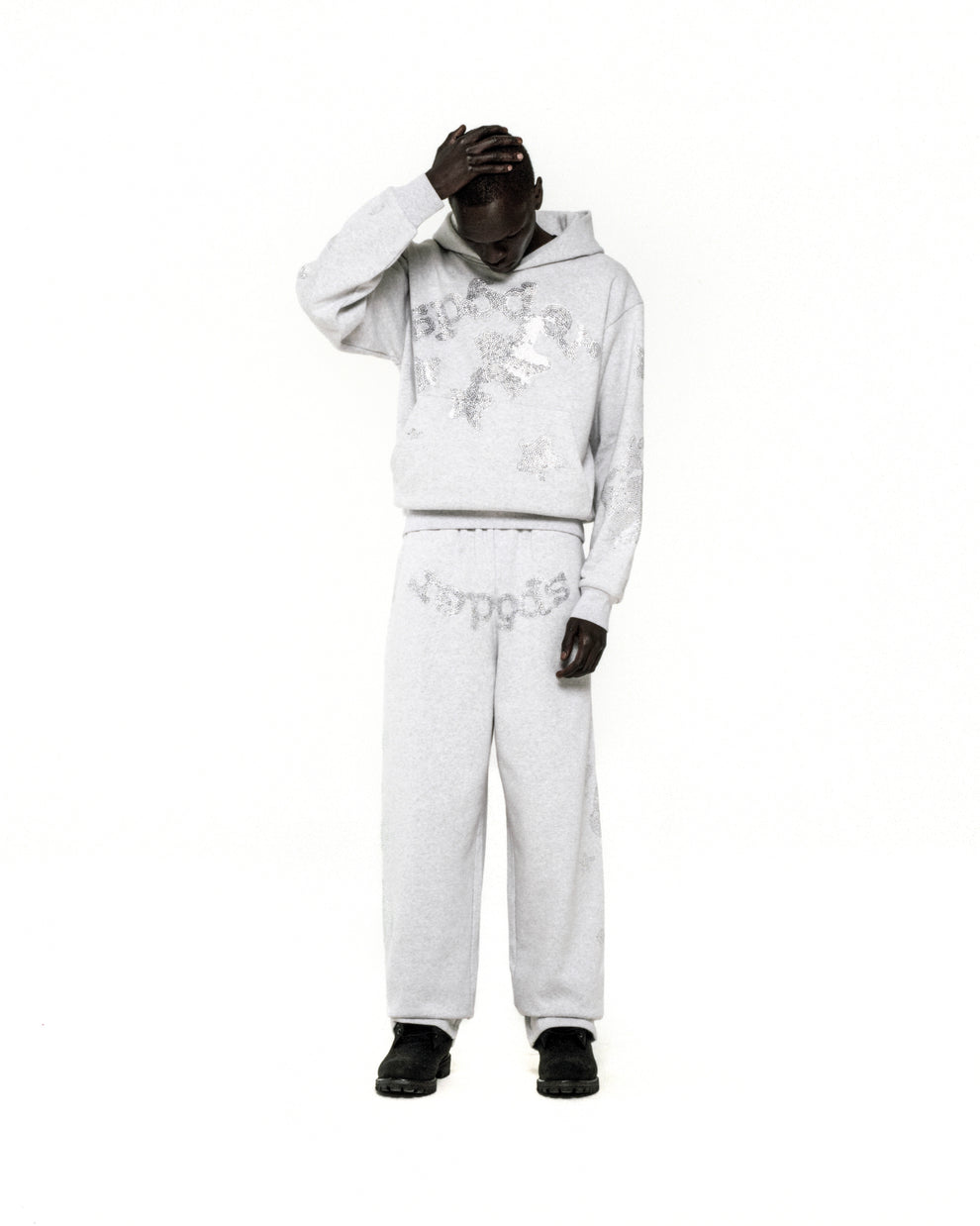 Light grey rhinestone embellished 'SP5DER' hoodie and sweatpants set on a model.