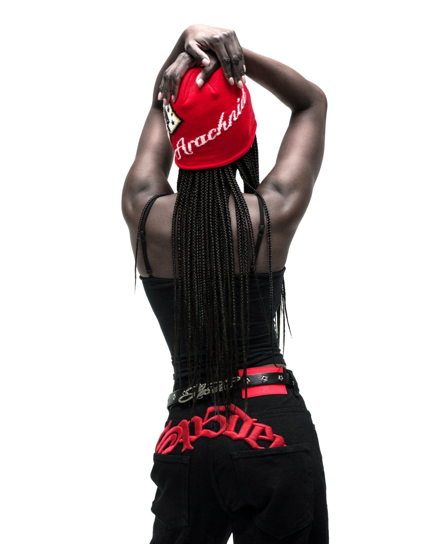 Red acrylic skully with "Arachnid" embroidery and varsity graphic, worn by a person with braids.