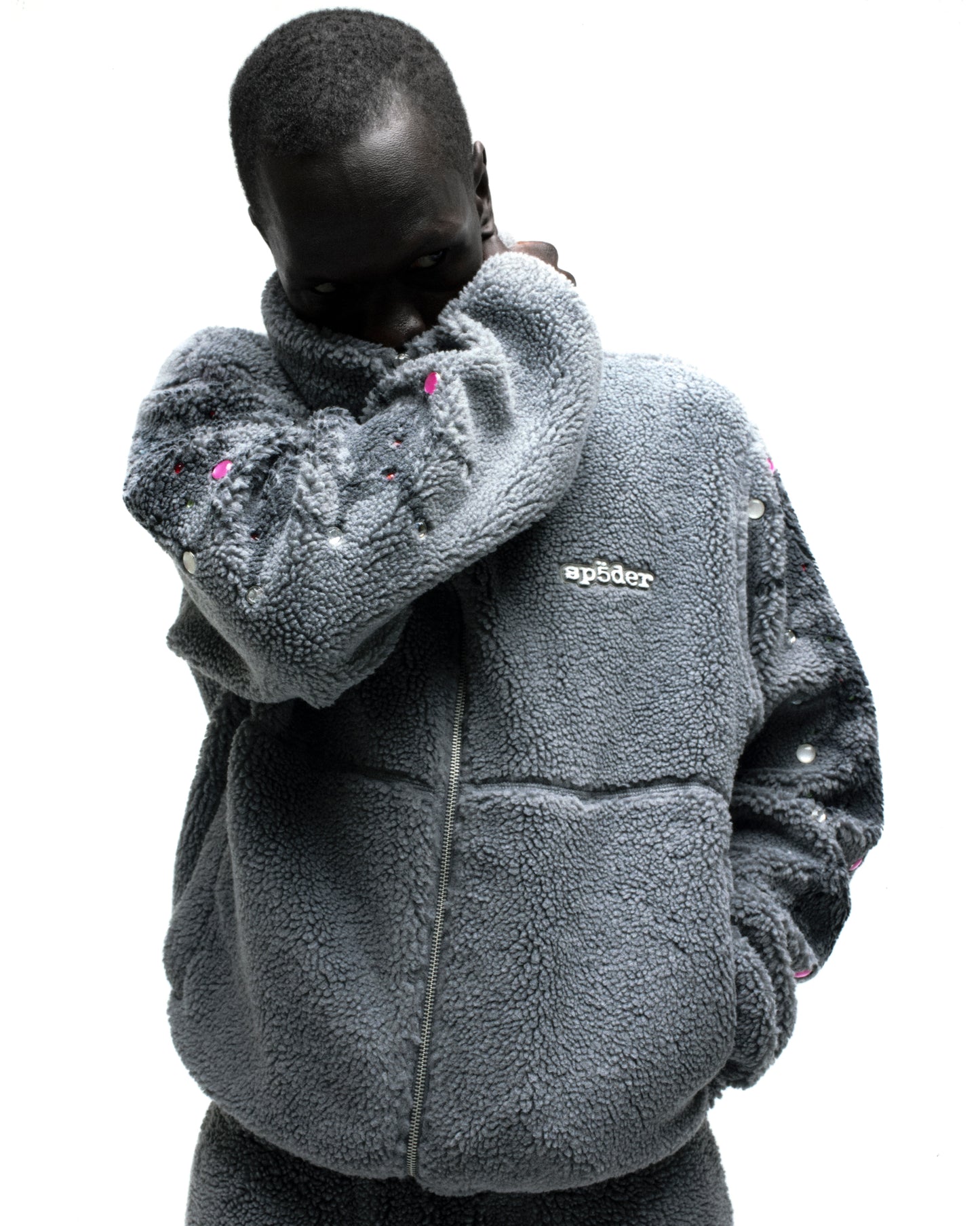 Gray sherpa fleece zip-up jacket with web print, pink rhinestones on sleeves, and "sp5der" logo.
