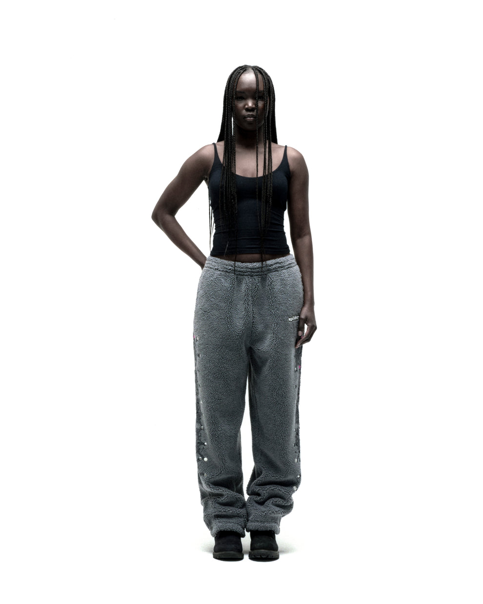 Gray sherpa fleece pants with rubberized logo patch, web print, and rhinestone embellishments down legs.