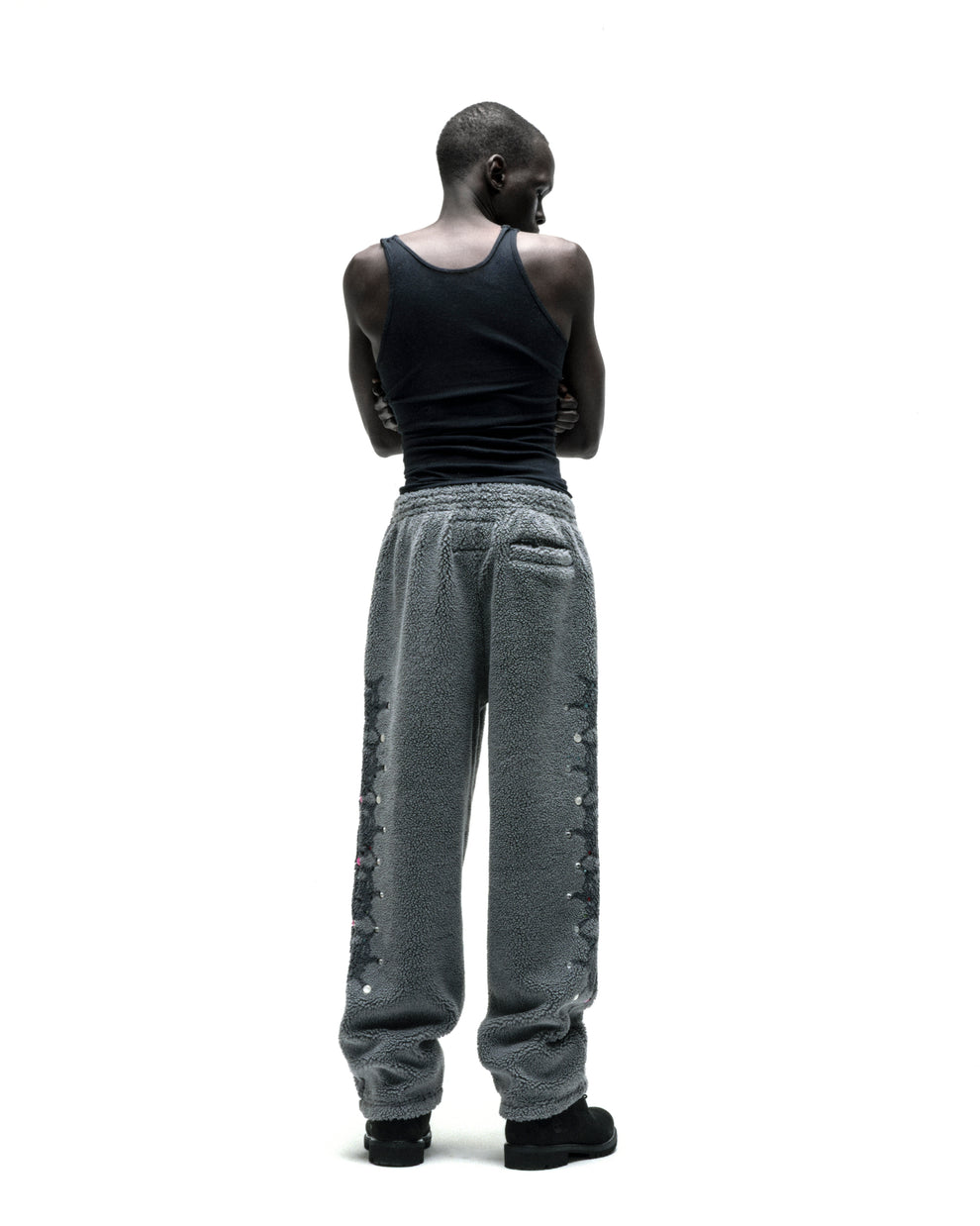 Gray sherpa fleece pants with web print, rhinestone embellishments, and a rubberized logo patch.