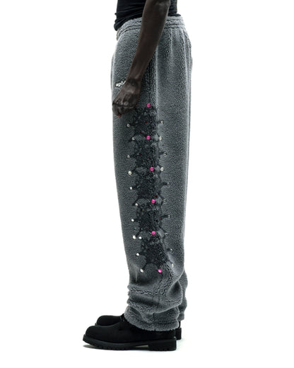 Gray sherpa fleece pants with web print, rhinestones, and rubberized logo patch on leg.