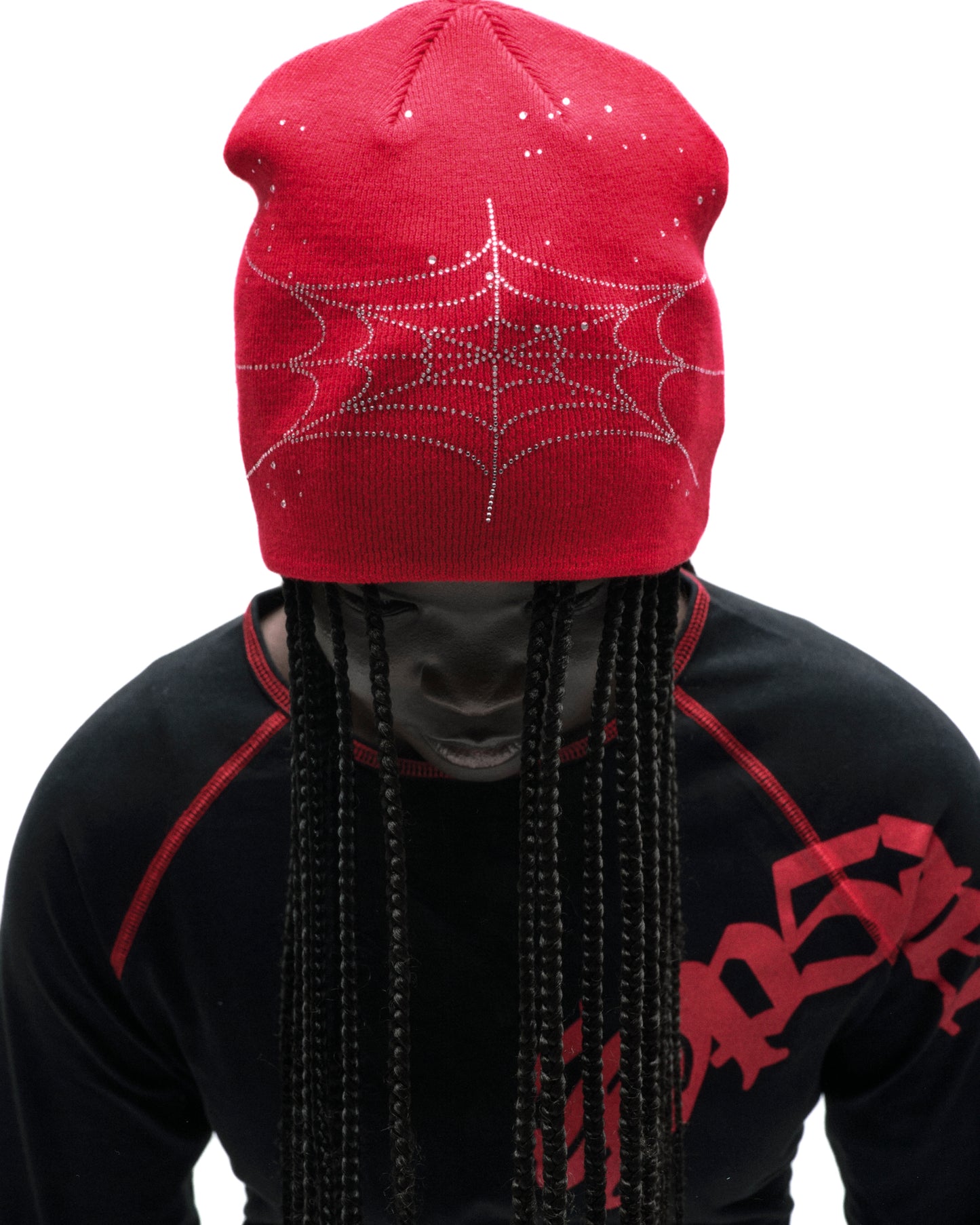Red acrylic rhinestone skullcap with a spiderweb design, worn by a person with braids.