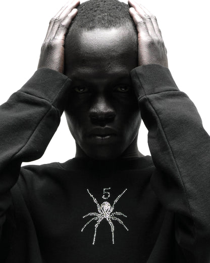 Black 100% cotton RHINESTONE TM CREWNECK with rhinestone spider graphic, worn by a person.