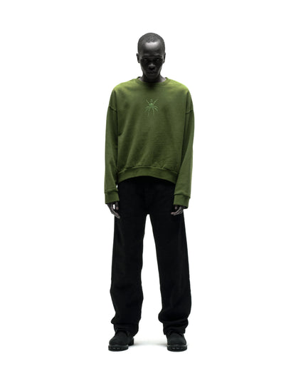 Model wearing a green RHINESTONE TM CREWNECK, 100% cotton brushed fleece with spider graphic.