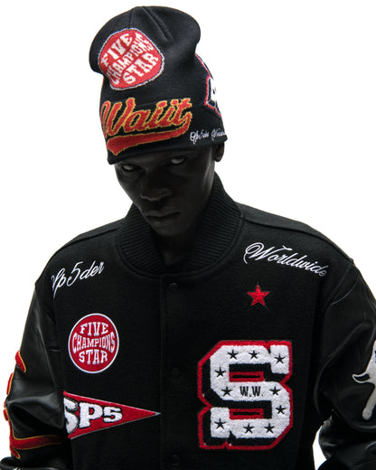 Black wool varsity jacket with leather sleeves, embroidered patches, and striped ribbed trim.