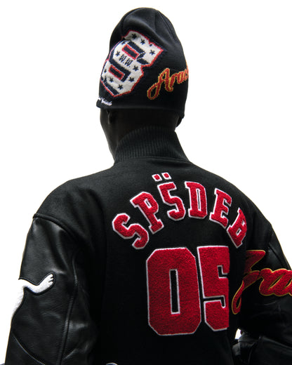 Black wool varsity jacket with leather sleeves, red embroidered "SP5DER 05" on back, and a patterned beanie.