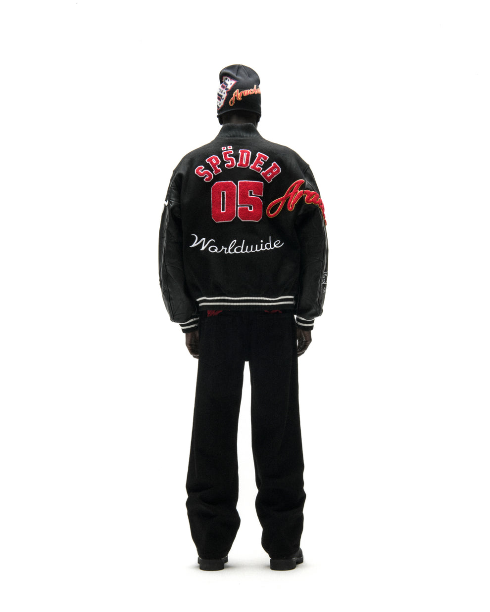Black wool varsity jacket with leather sleeves, red "SP5DER 05" embroidery, and "Worldwide" script on the back.