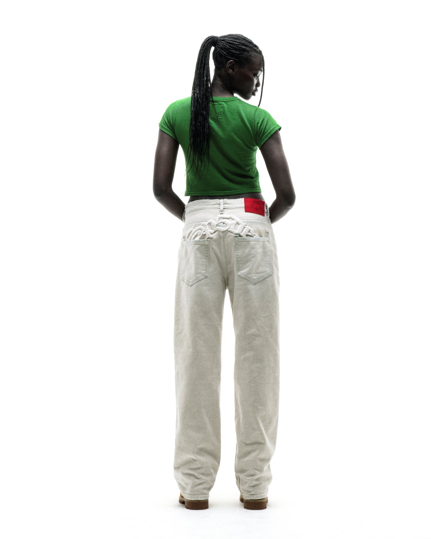 Model in green cropped cotton/spandex baby tee and light-colored baggy jeans, back view.
