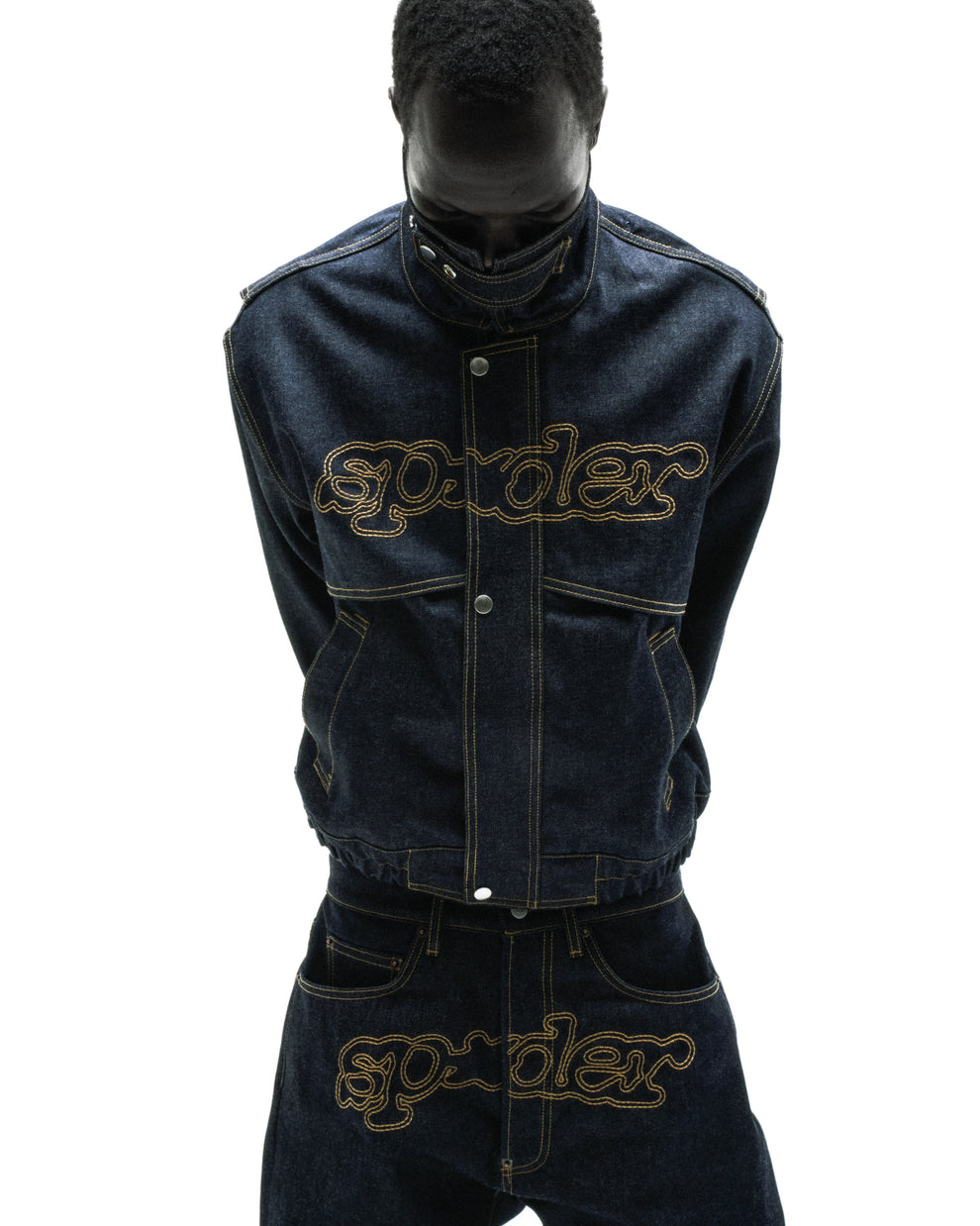 Dark wash denim jacket and jeans with "SP5DER" embroidered in gold across the chest and crotch.
