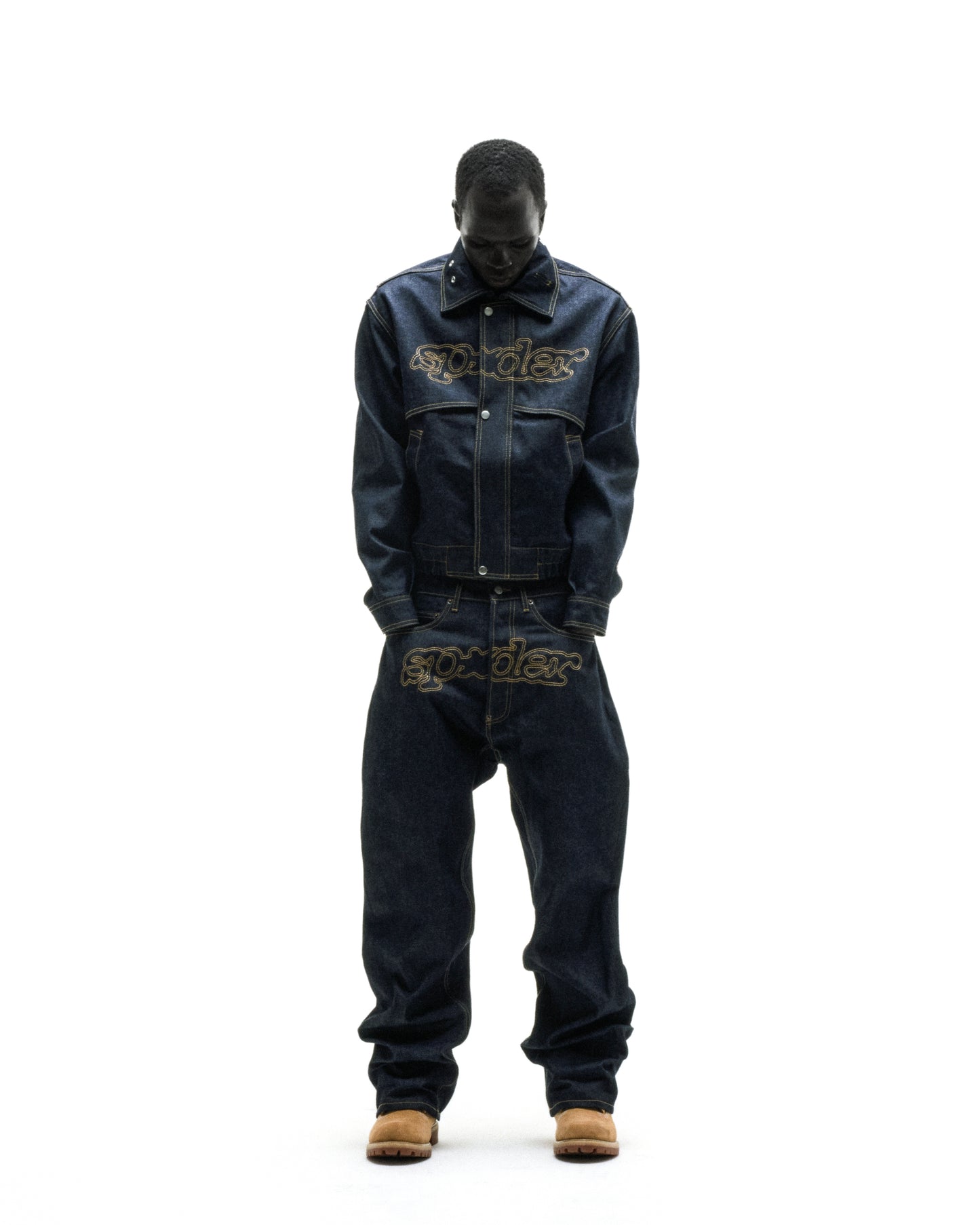 Dark wash denim jacket and jeans with embroidered "SP5DER" logos, worn by a person.