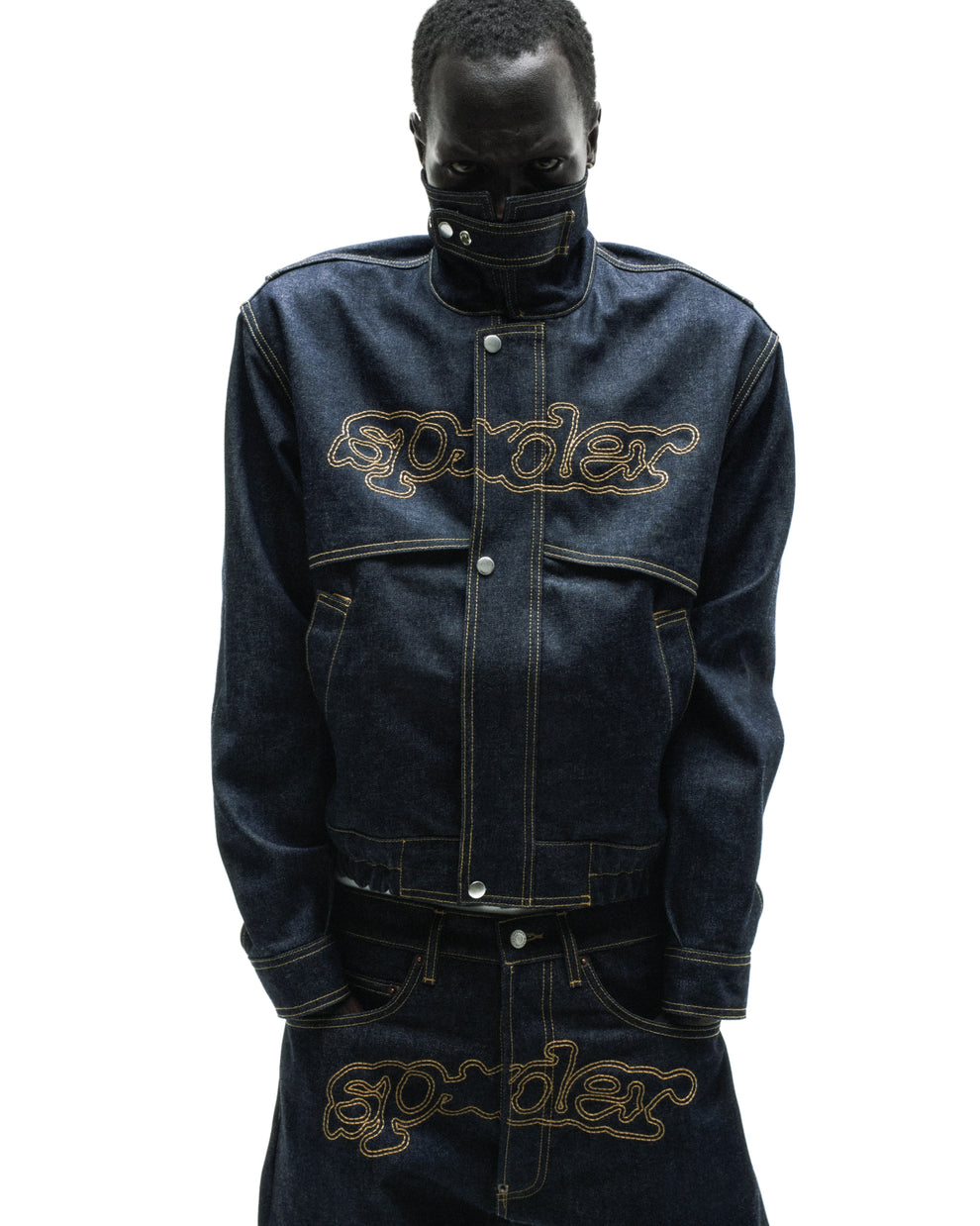 Dark wash denim jacket with yellow stitching, embroidered script logo, stand collar, and zipper placket.
