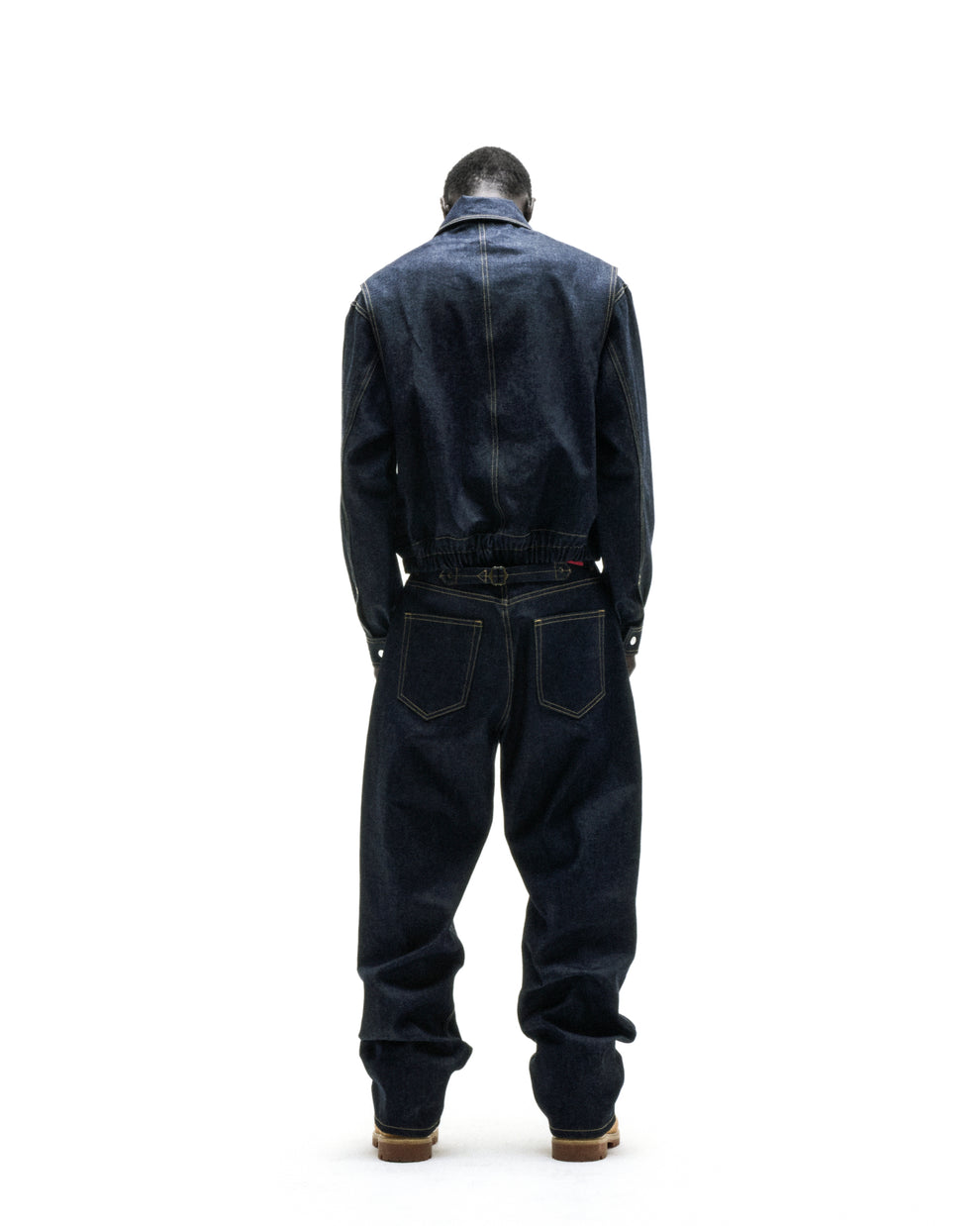 Dark wash denim jumpsuit with a jacket-style top and loose-fitting pants, viewed from the back.