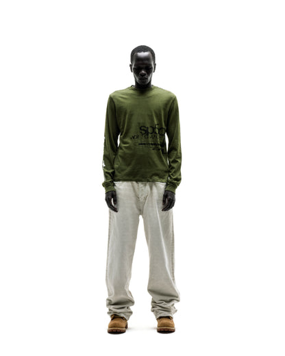 Dark-skinned model in an olive green cotton long sleeve tee with black graphic print, light linen pants, and brown boots.