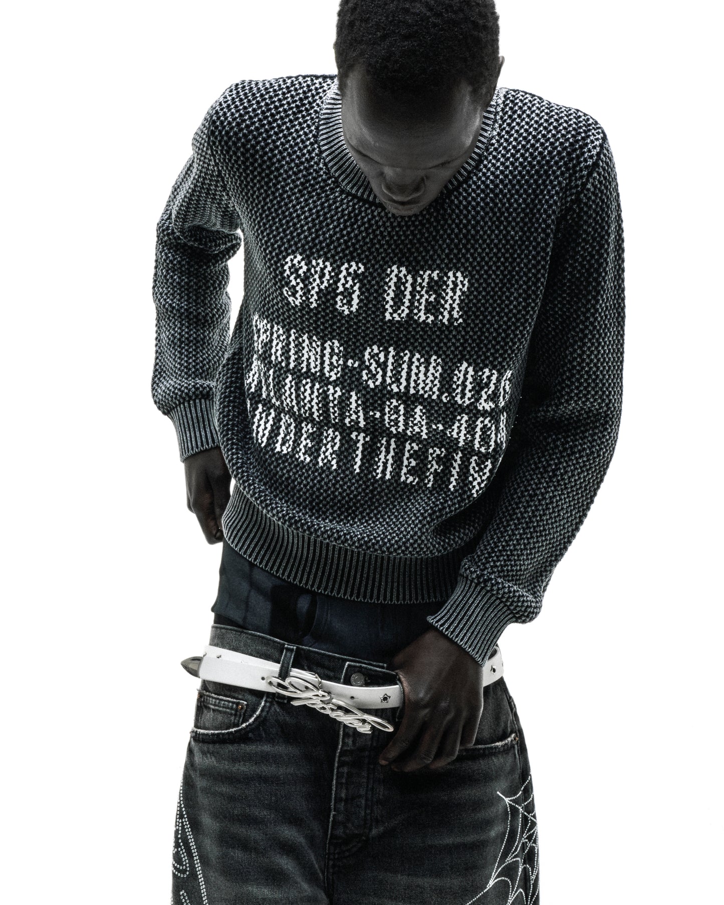 Black knit cotton sweater with white text print at chest, worn by a man.