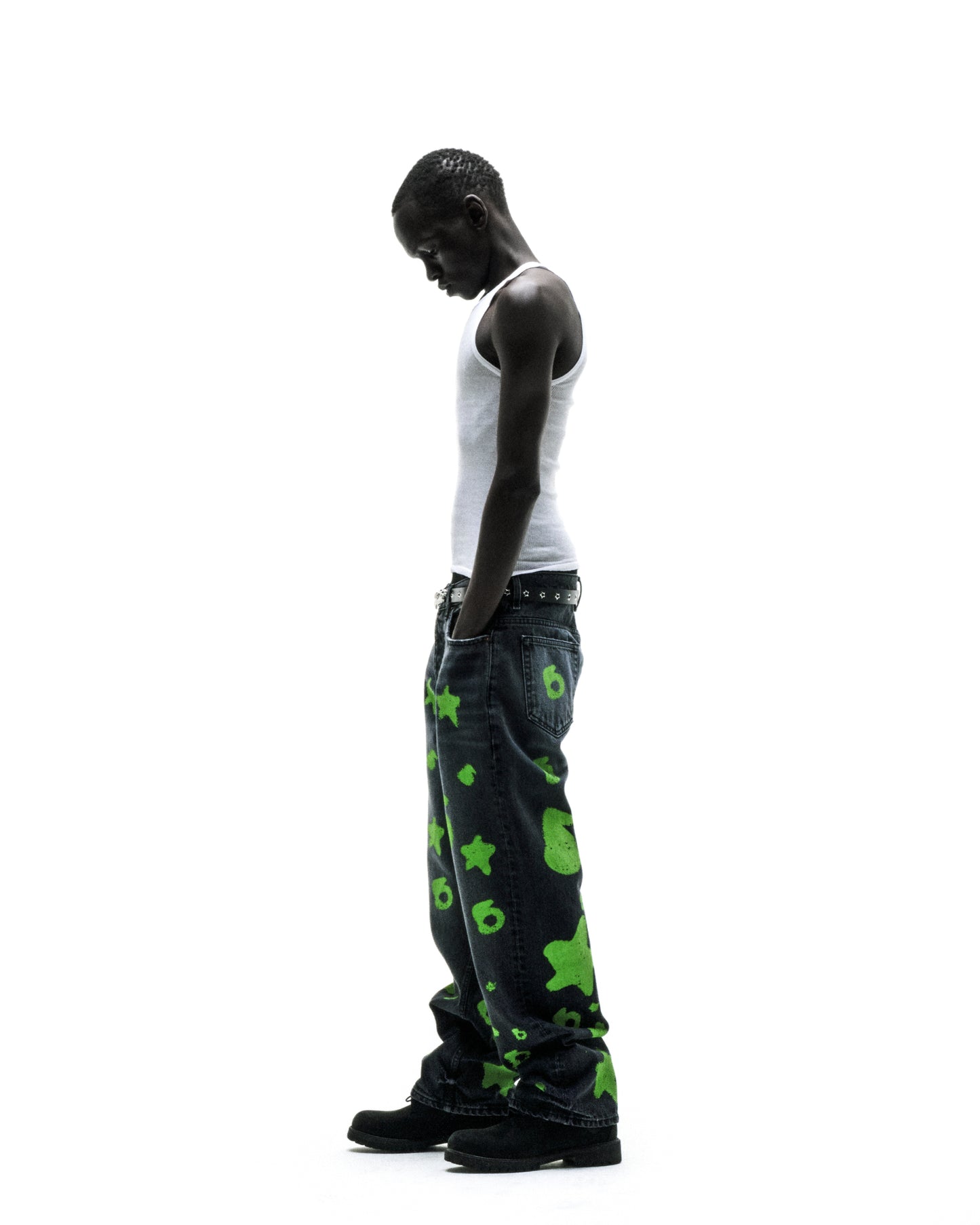 Man in faded wash BELUGA STAMP DENIM pants with green star and number 6 designs.